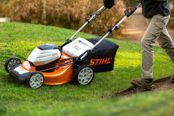 Commercial landscaper using STIHL battery-powered lawn mower for professional grass cutting in Ottawa.